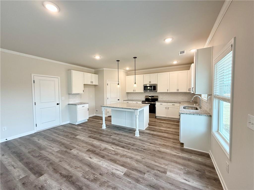 2506 Sunny Hill Road Buford, GA 30519 - Photo 10 of 25 a large kitchen with kitchen island a stove a sink dishwasher a refrigerator and white cabinets with wooden floor
