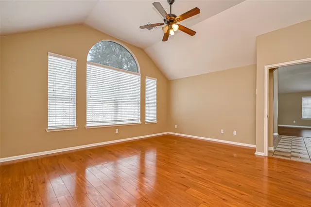 a view of an empty room with a window and wooden floor