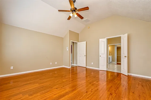 a view of an empty room with window and wooden floor