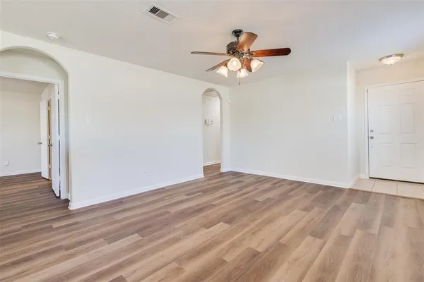a view of empty room with wooden floor and ceiling fan