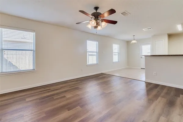 a view of an empty room with a window and wooden floor