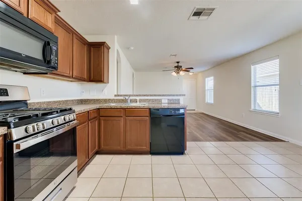a kitchen with stainless steel appliances granite countertop a stove a sink and a microwave