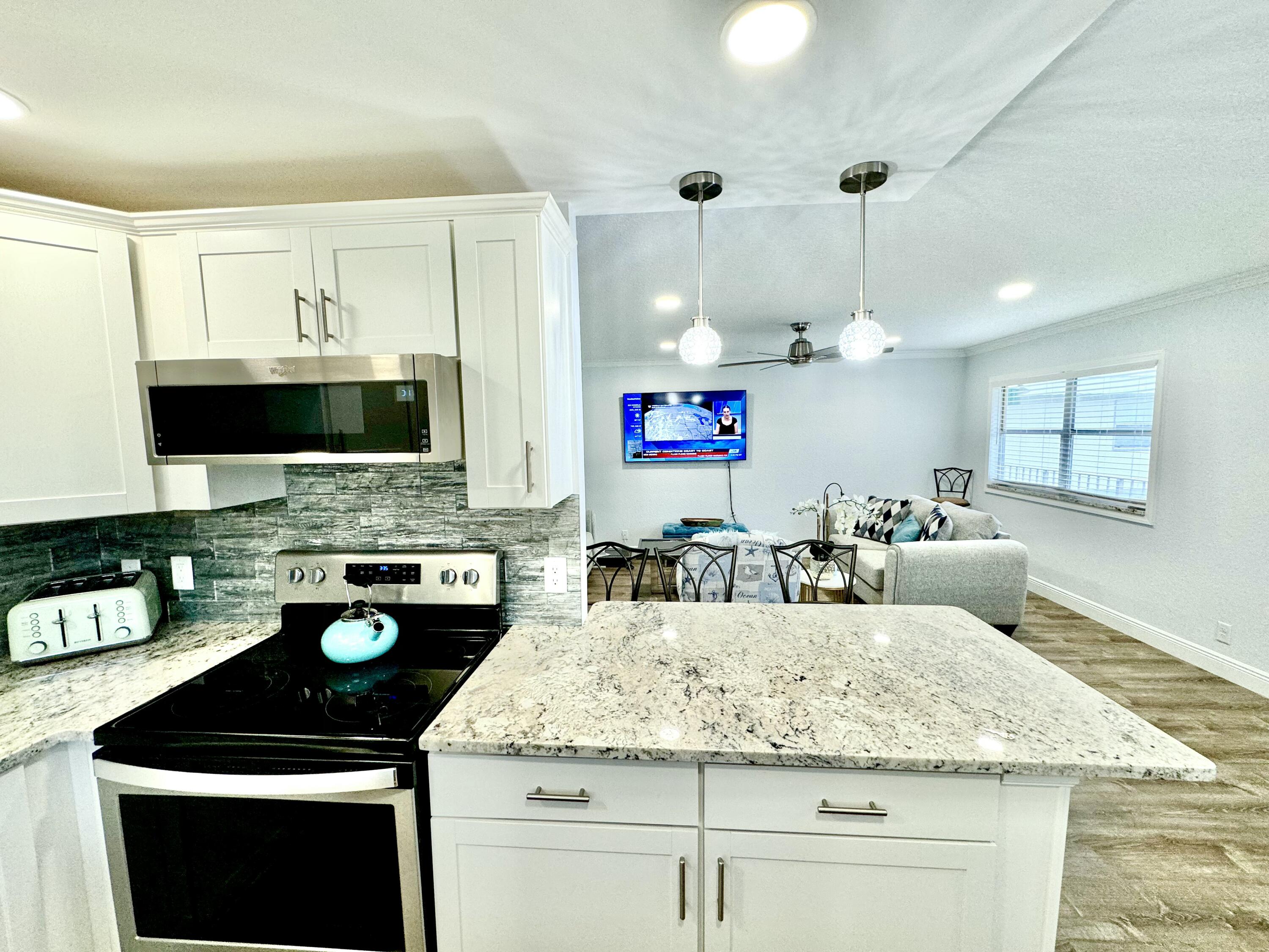 177 Brittany Terrace Delray Beach, FL 33446 - Photo 4 of 24 a kitchen with kitchen island granite countertop a sink a stove and cabinets