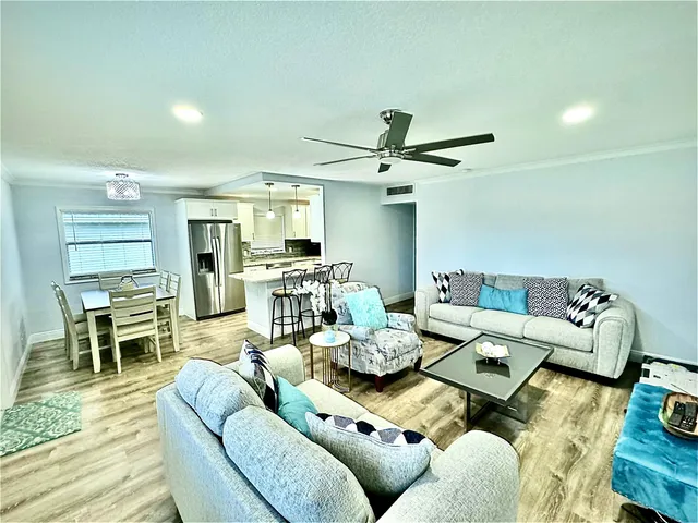 a living room with furniture kitchen view and a wooden floor