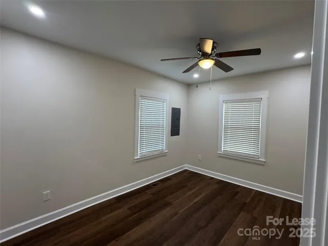an empty room with wooden floor ceiling fan and windows