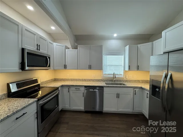 a kitchen with granite countertop a sink and steel appliances