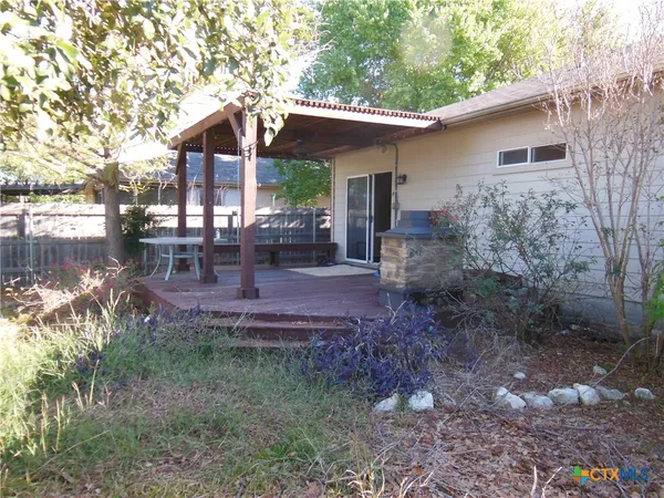 a view of a chair and table in backyard of the house