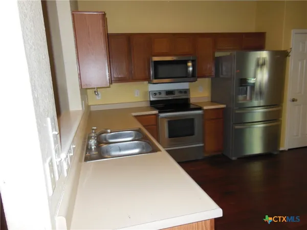 a kitchen with a refrigerator sink and wooden floor