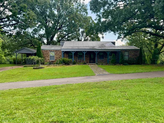 a view of a house with a big yard and large trees