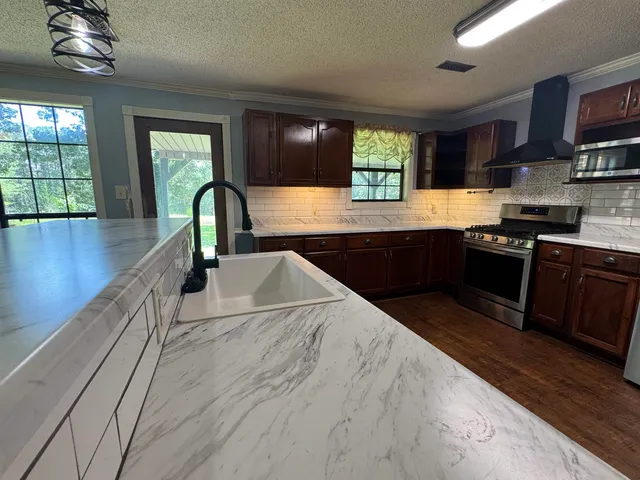 a kitchen with stainless steel appliances granite countertop a sink a stove and a wooden floors