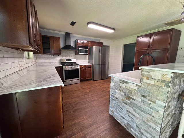 a kitchen with stainless steel appliances kitchen island granite countertop a stove and a sink