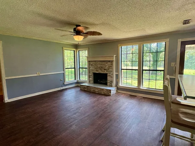 an empty room with wooden floor fireplace and windows
