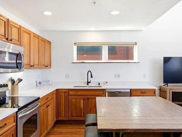 a kitchen with kitchen island granite countertop a sink a stove and a microwave