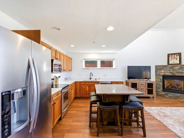a living room with stainless steel appliances furniture a fireplace and a flat screen tv