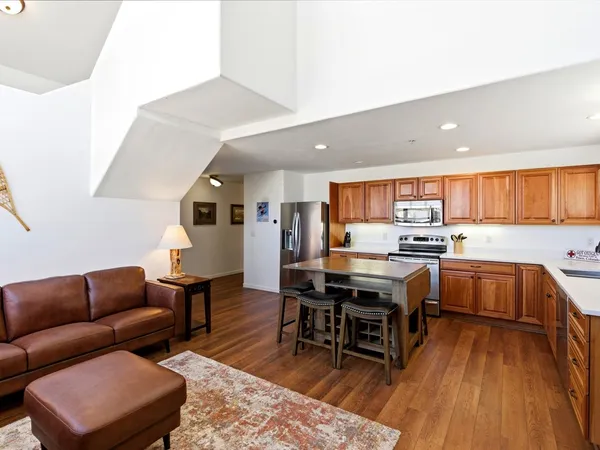 a living room with stainless steel appliances furniture and wooden floor
