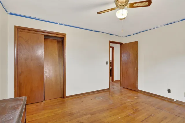 a view of empty room with wooden floor and fan
