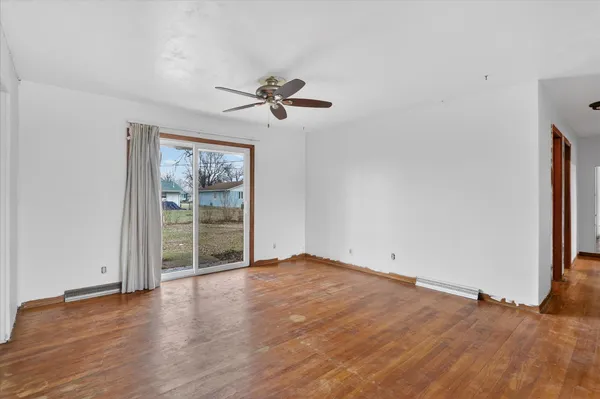 a view of empty room with wooden floor and fan