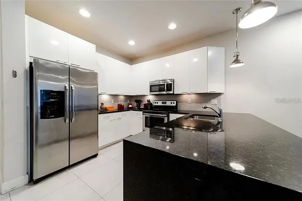 a kitchen with stainless steel appliances granite countertop a sink a stove and a refrigerator