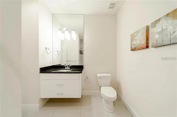 a bathroom with a granite countertop toilet sink and mirror