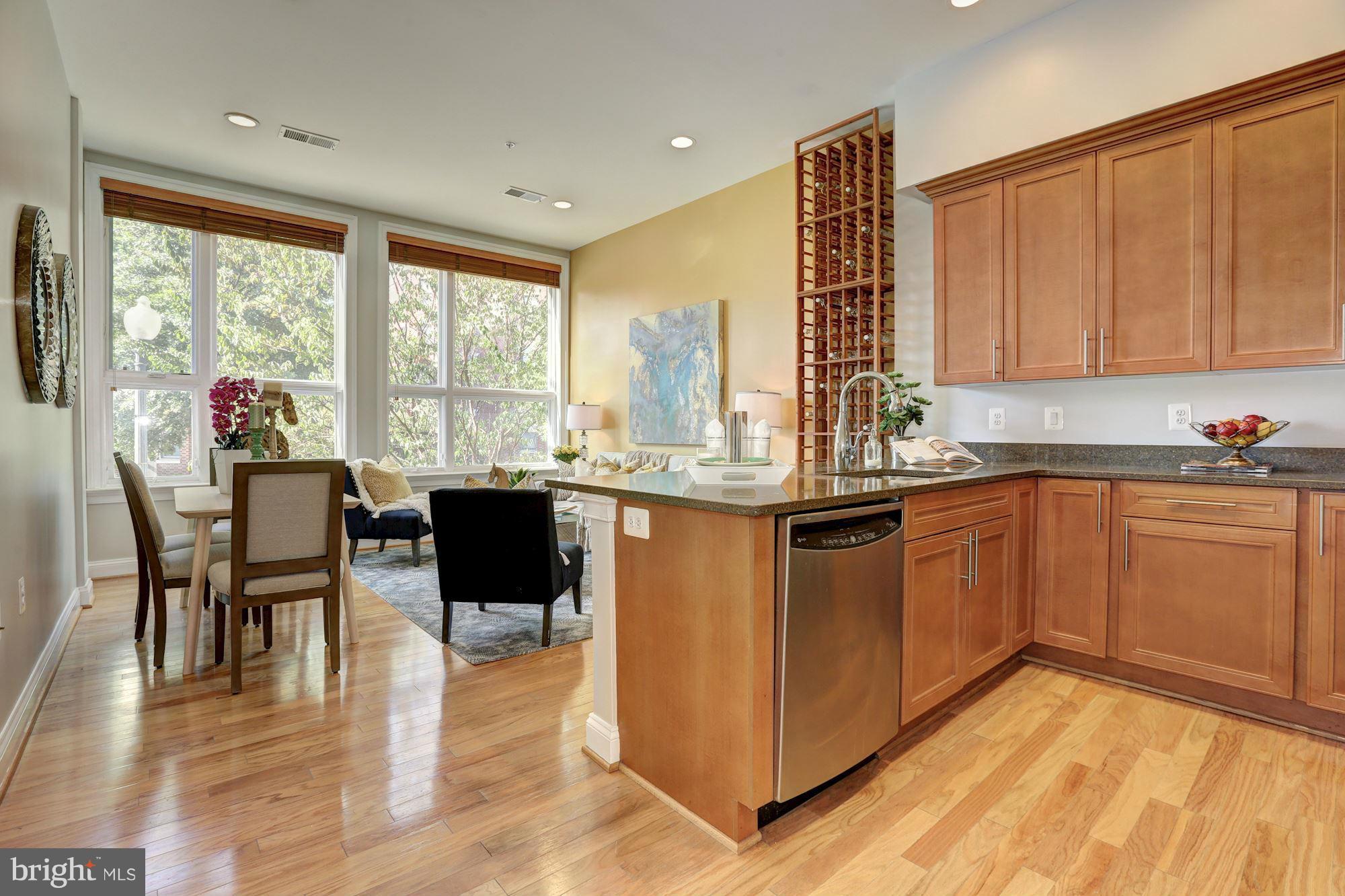 1407 W Street Northwest, Unit 202 Washington, DC 20009 - Photo 7 of 30 a kitchen with stainless steel appliances granite countertop a stove a sink a microwave dining table and chairs