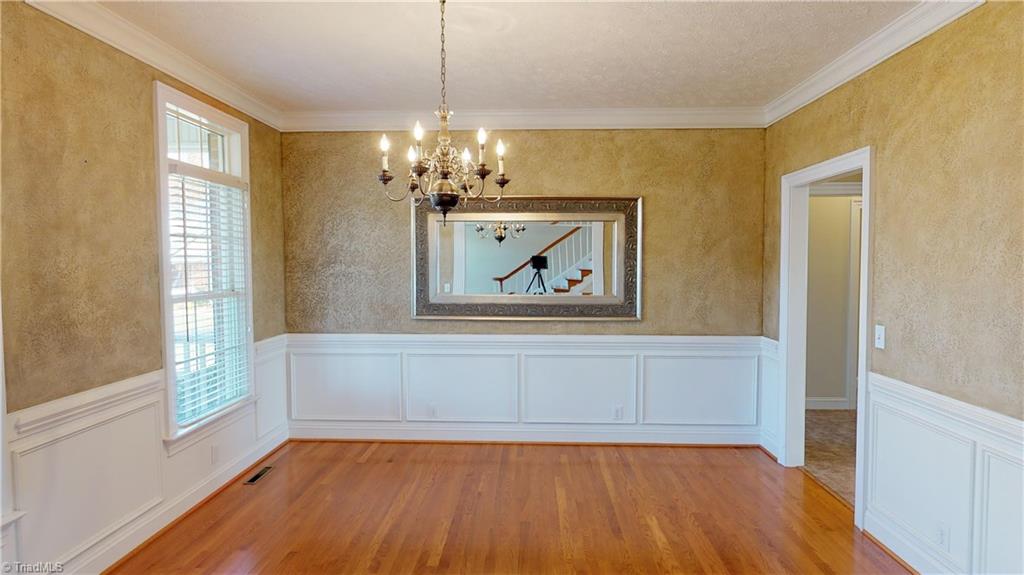 256 Stonecroft Road Mount Airy, NC 27030 - Photo 9 of 30 Dining room with hardwood floors, wainscoting, textured walls and crown molding.