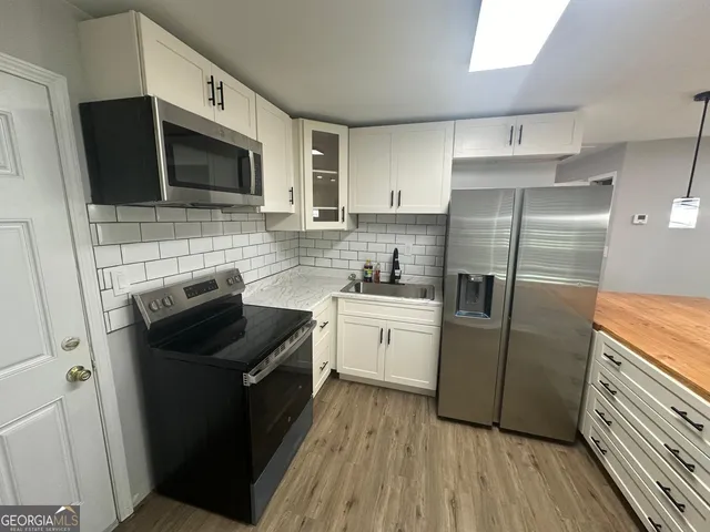 a large kitchen with stainless steel appliances a refrigerator and a stove top oven