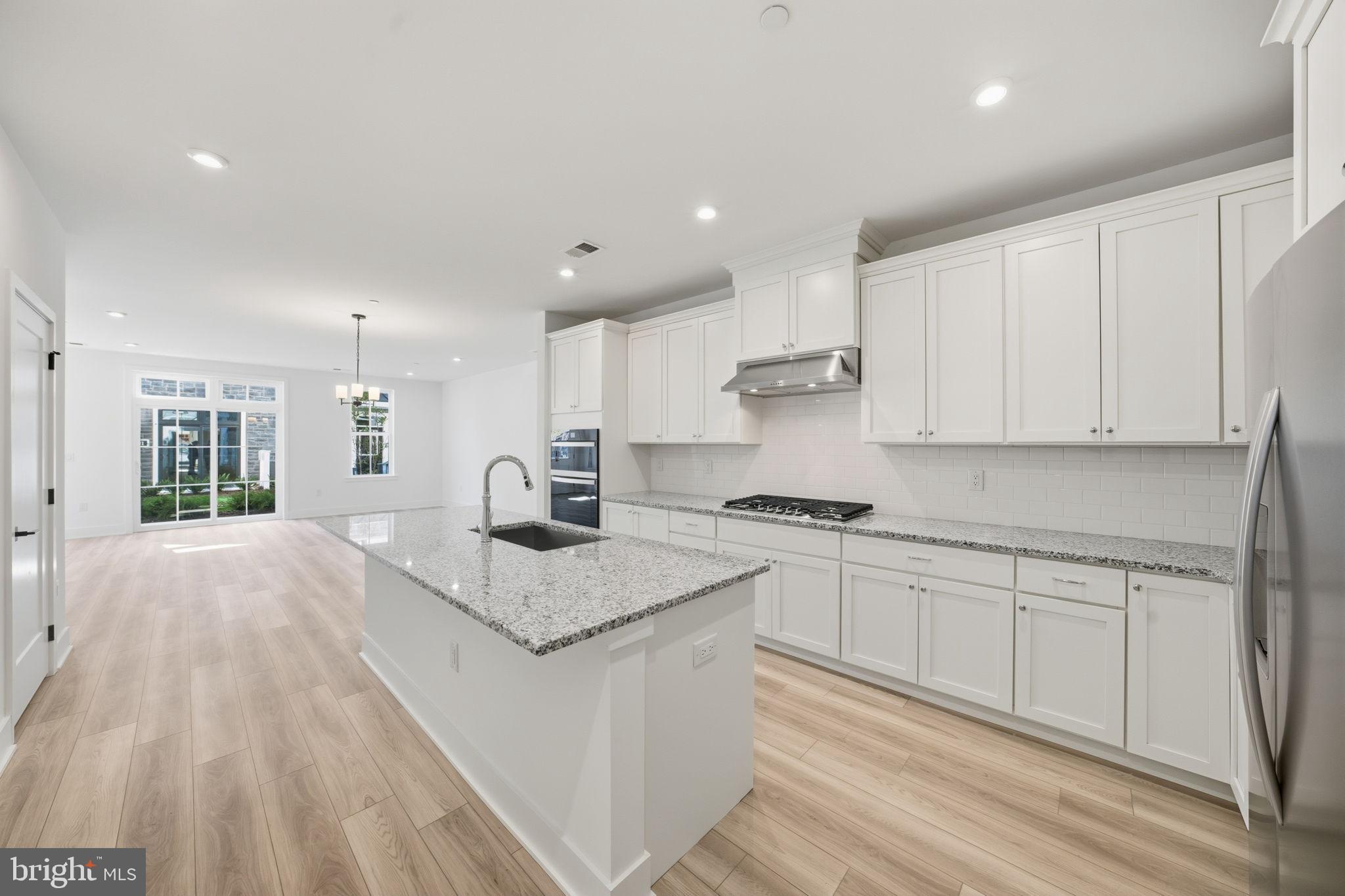 8101 Donatello Drive Princeton, NJ 08540 - Photo 9 of 26 a kitchen with stainless steel appliances granite countertop a sink dishwasher a stove and white cabinets with wooden floor