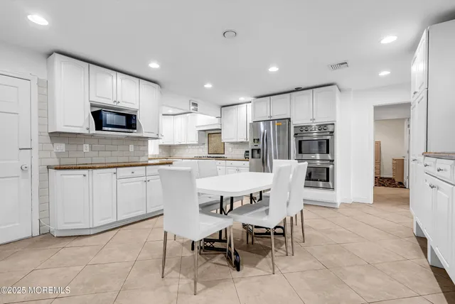 a kitchen with stainless steel appliances granite countertop a stove a sink a microwave a refrigerator and white cabinets