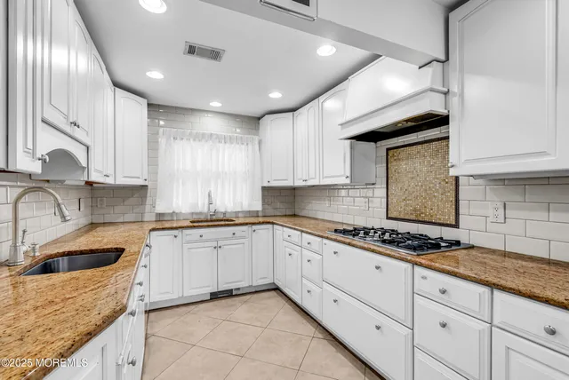 a kitchen with granite countertop a sink a stove and cabinets