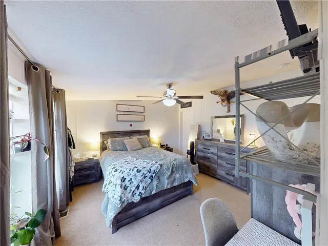 a bedroom with a bed dresser and a large window