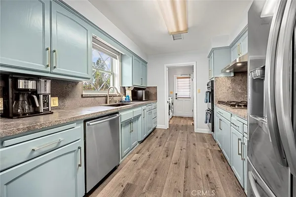 a kitchen with cabinets stainless steel appliances and wooden floor