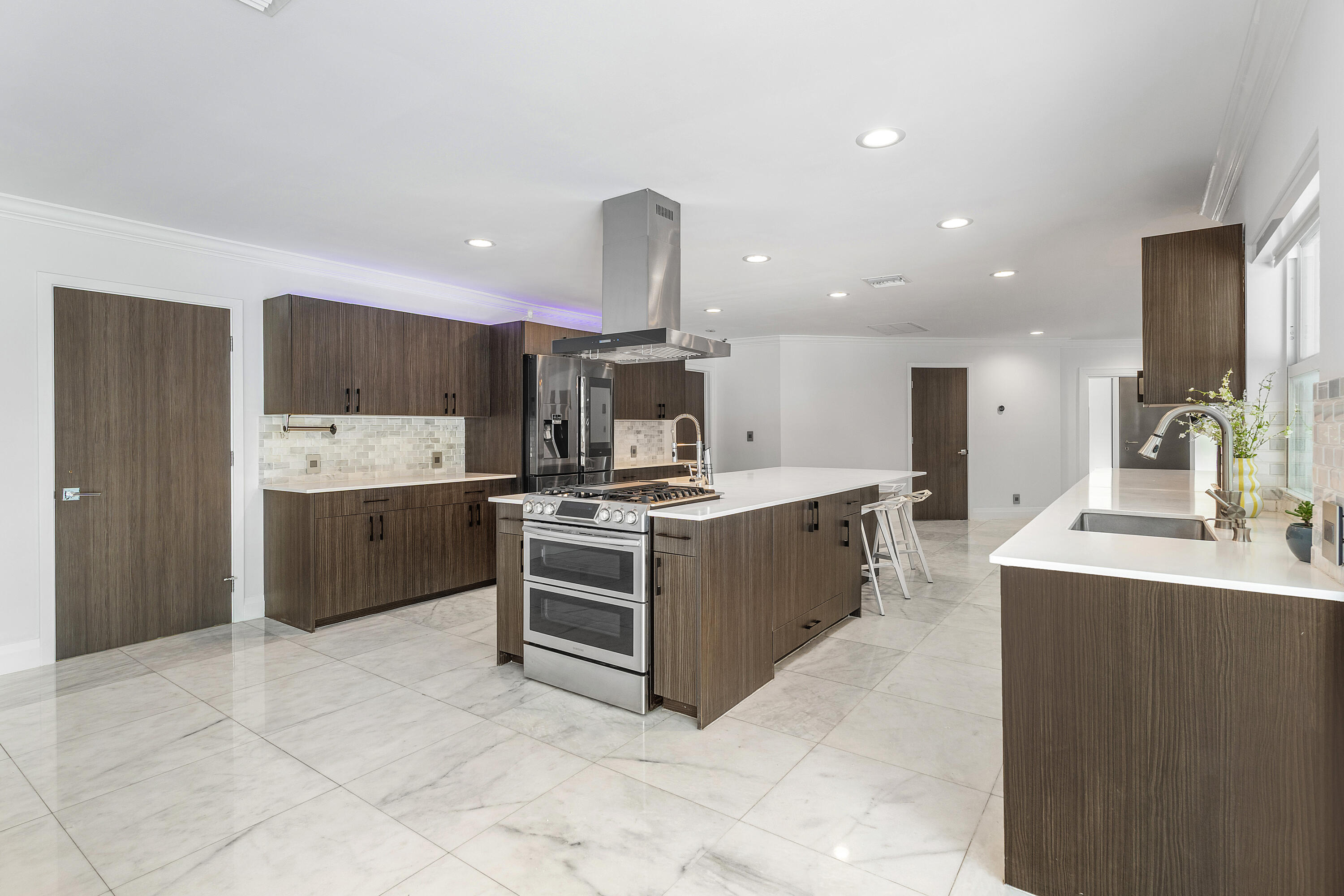 960 Southwest 18th Street Boca Raton, FL 33486 - Photo 10 of 40 a large kitchen with stainless steel appliances a large counter top a stove a chimney a sink and a refrigerator