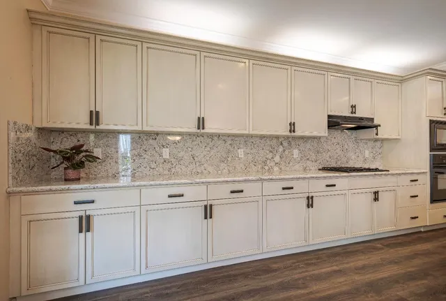 a kitchen with granite countertop white cabinets and sink
