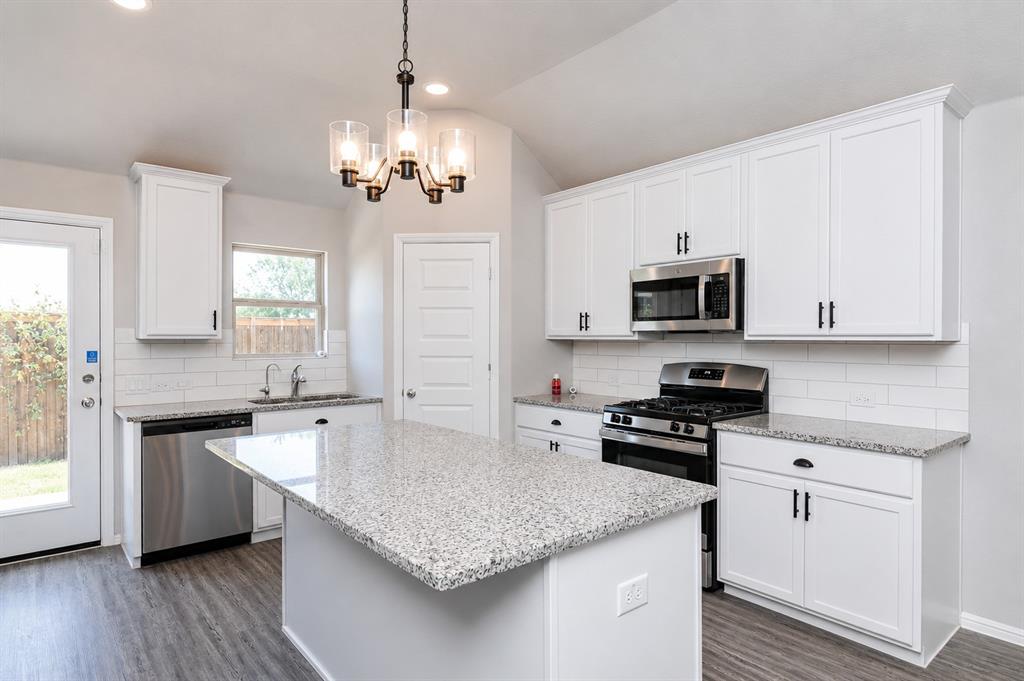 3344 Duncan Way Corinth, TX 76210 - Photo 11 of 38 Kitchen featuring white cabinetry, granite countertops, stainless steel appliances, a center island, and wood-finish flooring