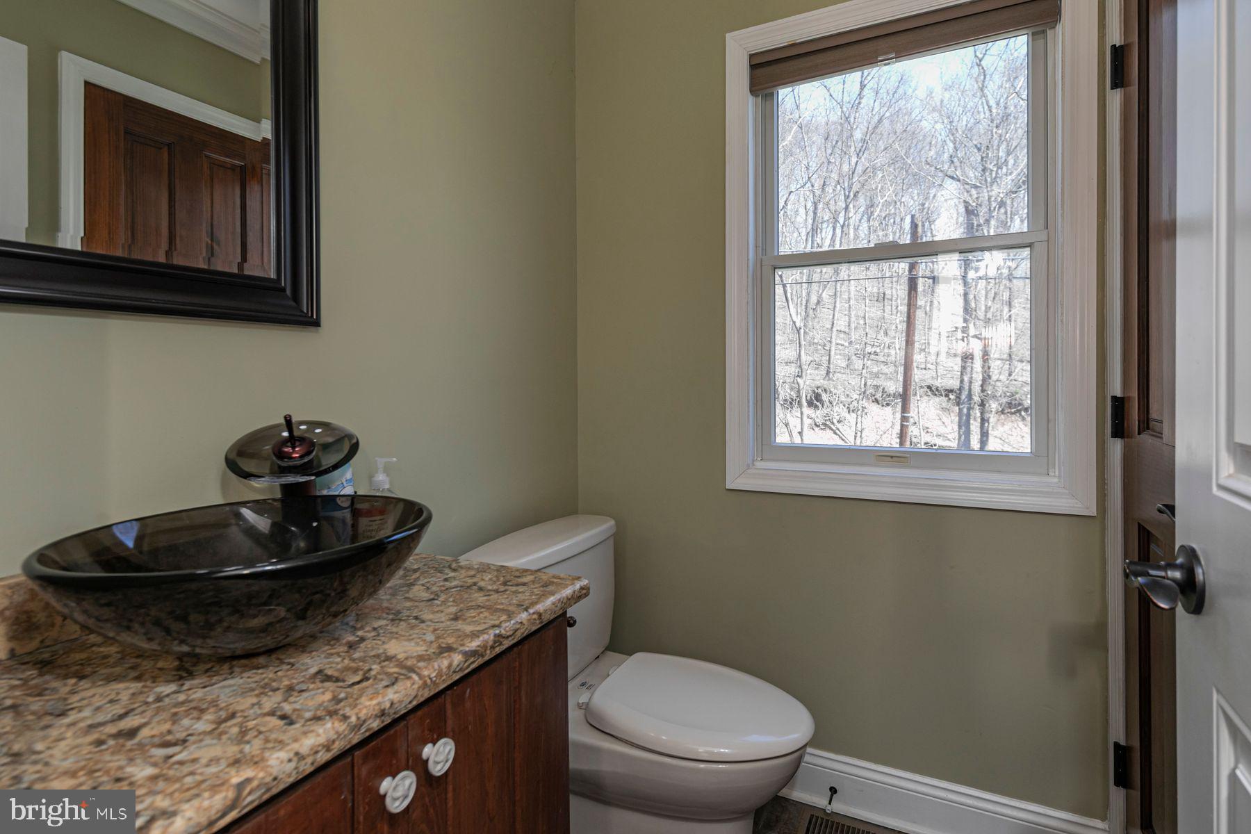 310 Hollow Road Skillman, NJ 08558 - Photo 14 of 32 a bathroom with a granite countertop sink a toilet and a window