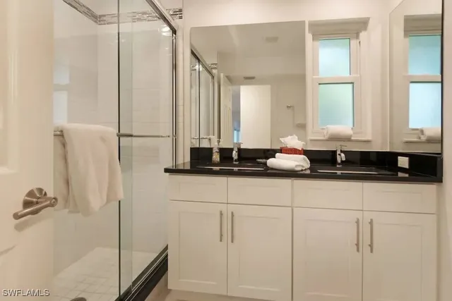 a bathroom with a granite countertop sink a mirror and a shower