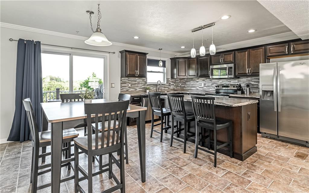138 Rylie Drive Harmony, PA 16037 - Photo 8 of 23 a kitchen with stainless steel appliances granite countertop a stove a refrigerator a kitchen island a table and chairs in it