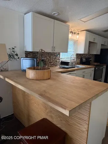 a large white kitchen with kitchen island granite countertop a sink a stove and cabinets