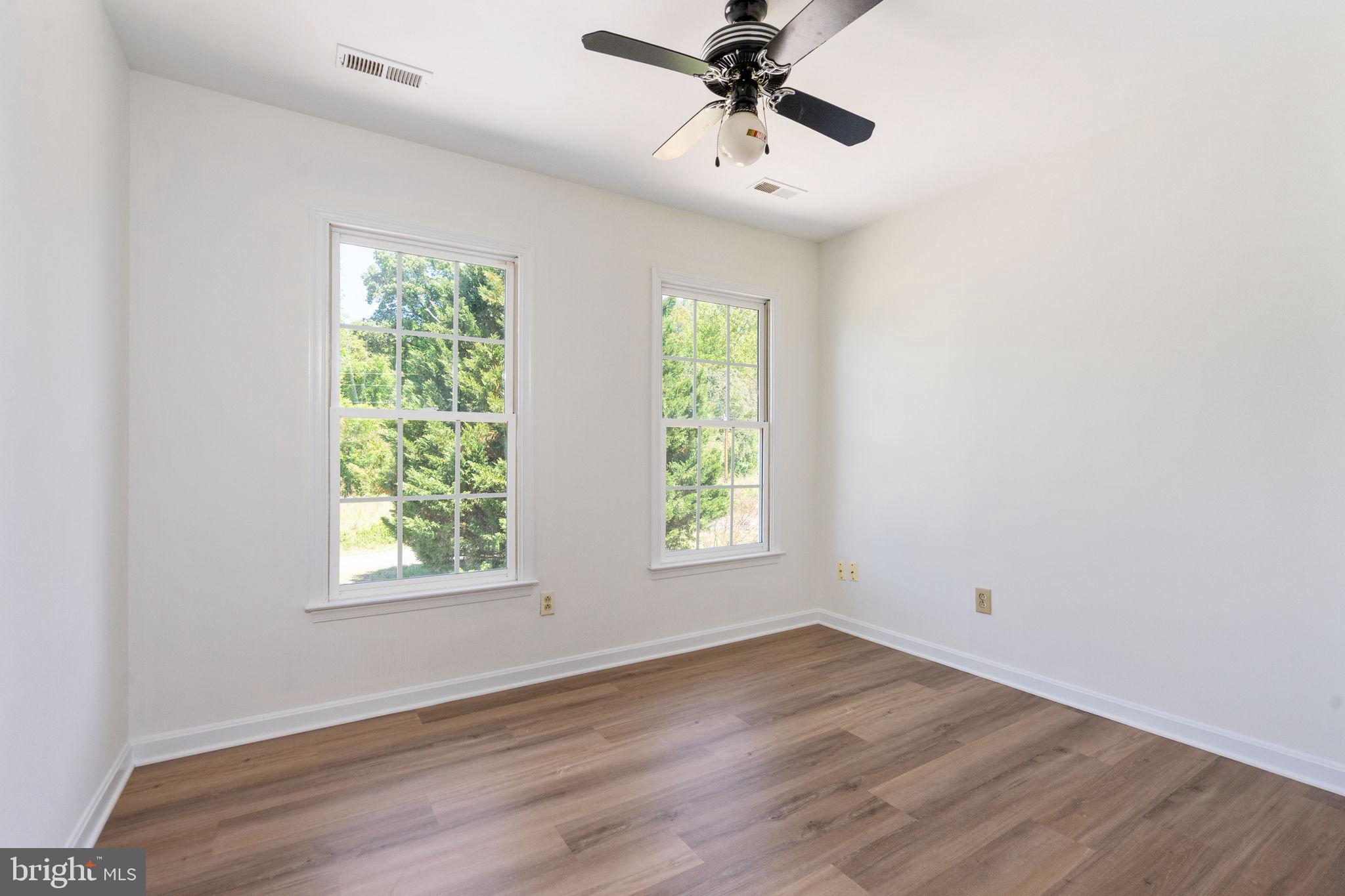 16456 Antioch Road Milford, VA 22514 - Photo 15 of 27 an empty room with wooden floor fan and windows