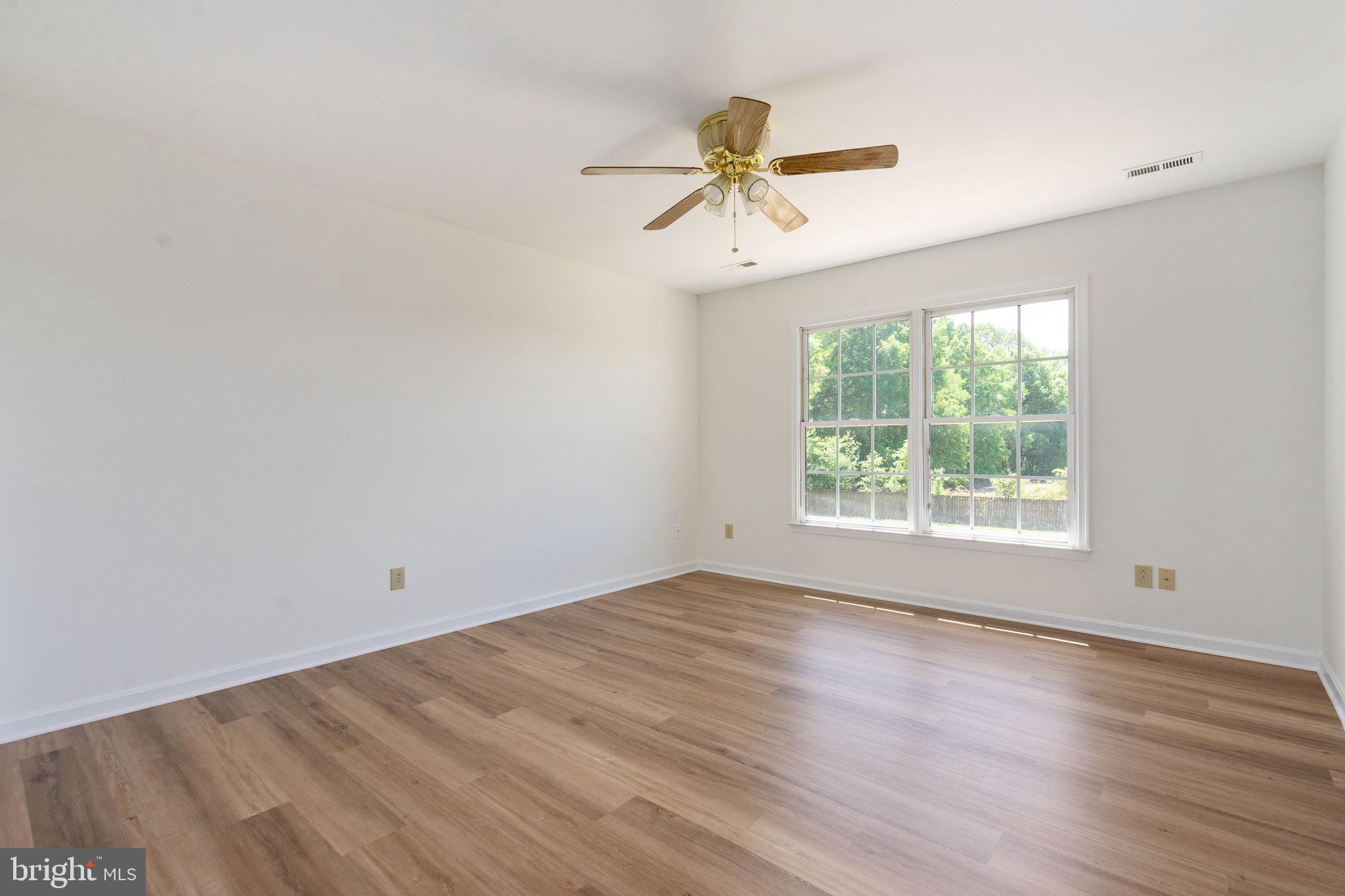 16456 Antioch Road Milford, VA 22514 - Photo 16 of 27 an empty room with wooden floor fan and windows