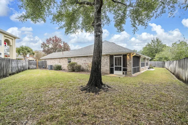 a backyard of a house with plants and tree with wooden fence