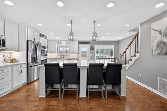 a kitchen with kitchen island granite countertop lots of wooden cabinets a dining table and appliances