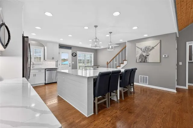 a large kitchen with stainless steel appliances kitchen island granite countertop a large cabinets a sink and a stove