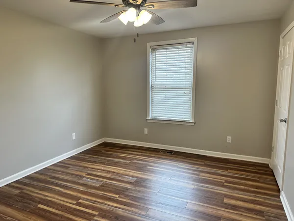 a view of an empty room with wooden floor and a window