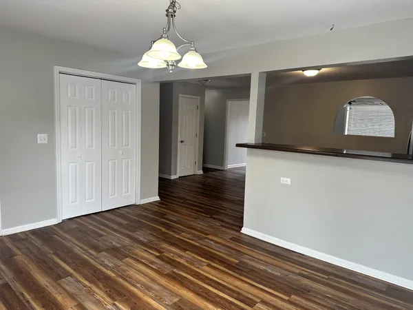 a view of a hallway with wooden floor and chandelier