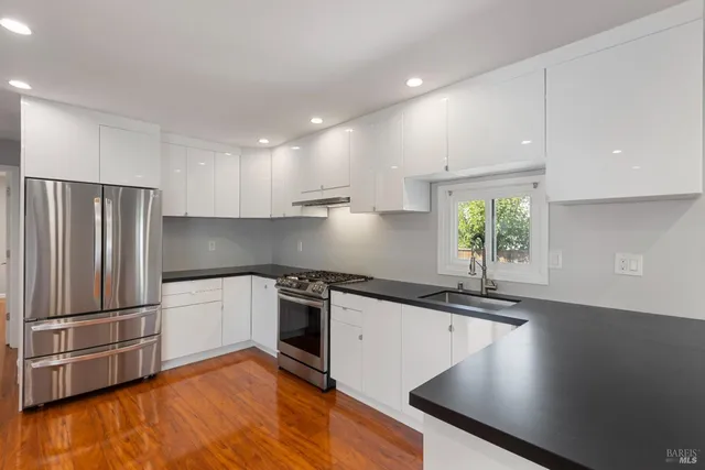a kitchen with stainless steel appliances granite countertop a sink a stove and a refrigerator