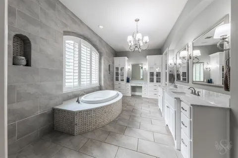 a large spacious bathroom with a granite countertop sink a mirror and a bathtub