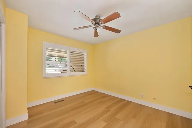 an empty room with a window and a fan