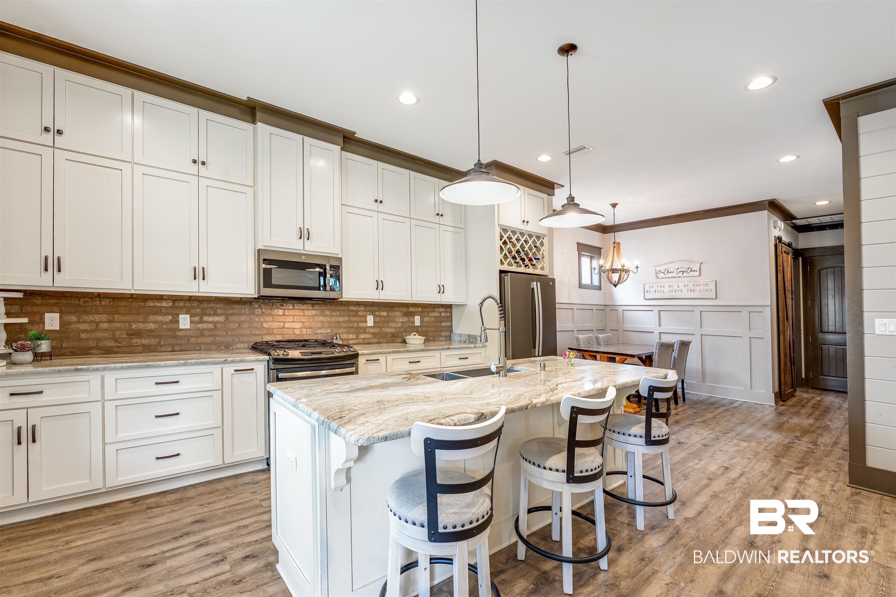 1119 Pink Poppy Lane Foley, AL 36535 - Photo 20 of 38 Kitchen featuring a breakfast bar area, hanging light fixtures, white cabinets, stainless steel appliances, gas stove, farmhouse deep sink, and light stone countertops