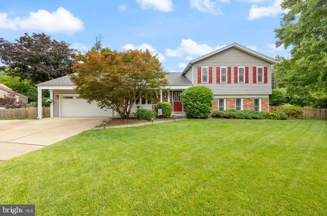 a view of a house next to a big yard and large trees
